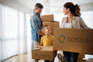 Happy young family with children moving with boxes in a new apartment house.