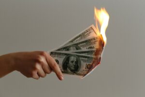 A hand holding money that has been set alight