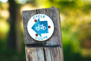 Cycle Route sign on wooden post. Trees in the background.