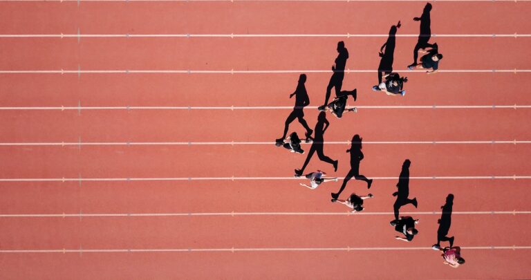 Aerial view of runners on a race track. Shadows are evident.